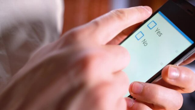 es or No - checkbox vote button on the screen of mobile phone. Man Hand holding smartphone with Yes checkbox. Confirm majority check symbol on the phone