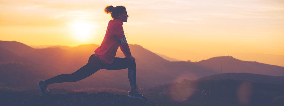Silhouette of athletic girl doing stretching after a great jog in the mountains at sunset. Sport tight clothes.