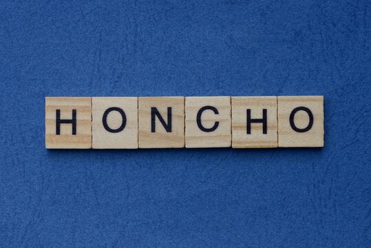  text on gray word honcho in small wooden letters with black font on a blue background