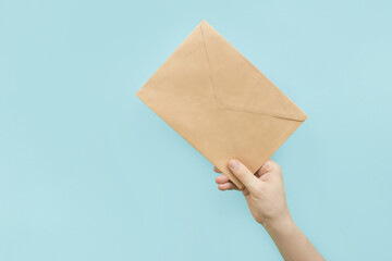 A man holding a craft brown envelope on blue background. 