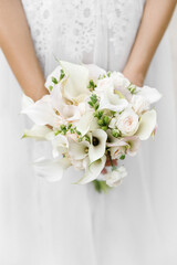 Bride holding a wedding bouquet with callas, roses close up. 