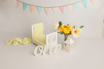 Spring yellow flowers next to wooden pastel baby bed with decor in white baby's room, copy space concept. Stylish baby bed near light wall in interior of children's room. 
