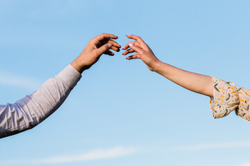 two hands reaching each other with their fingers against the sky. touch, touch, art minimal symbol....