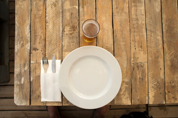 Fototapeta na wymiar plate, cutlery, glass beer on rustic wooden planes table restaurant