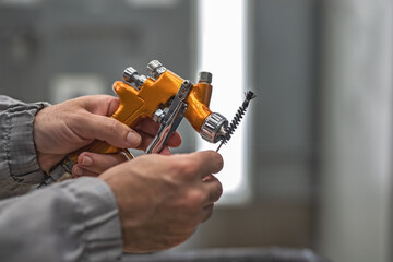 The hands of an employee of the shop painting cleaning spray gun