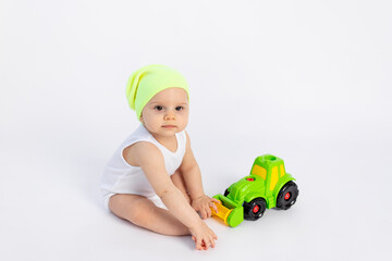 cute baby boy in a white bodysuit on a white isolated background playing with a typewriter, early development of children, baby 8 months among toys, space for text