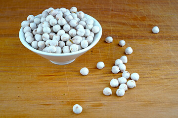 Plateful of Organic White chickpeas and Spilled White chickpeas on Wooden Background