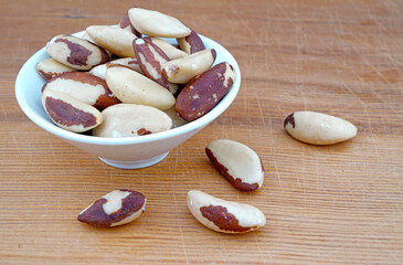 Plateful of Organic Brazil nuts and Spilled Brazil nuts on Wooden Background