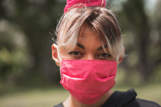 The girl in pink medical mask on nature background closeup