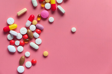 Top view of colorful pills spilling on pink background 