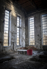 Old empty industrial abandoned factory, dirty interior with old red chairs, moody bright light