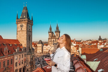 young woman with a cocktail on the roof in the center of Prague overlooking the Old Town Square