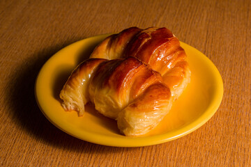 A couple of croissants on a yellow plate.