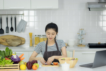 Asian young woman with glass of orange juice sitting at kitchen table,Health food concept