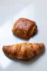 Fresh homemade croissant on white marble background.
