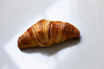 Fresh homemade croissant on white marble background.