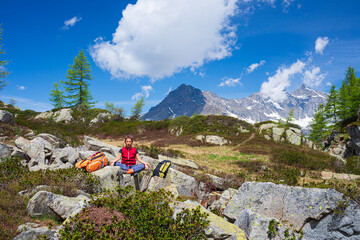 Woman meditating in natural environment on the mountains. One person sitting on rock in lotus pose in beautiful alpine ambient.
