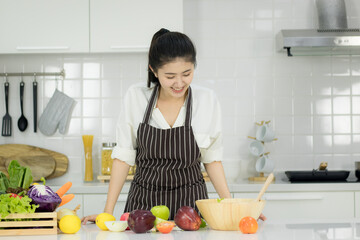 Asian young woman with glass of orange juice sitting at kitchen table,Health food concept
