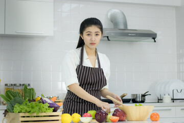 Asian young woman with glass of orange juice sitting at kitchen table,Health food concept