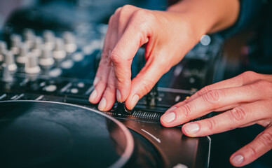 DJ Hands creating and regulating music on dj console mixer in concert nightclub stage.