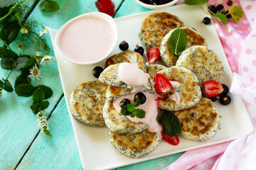 Summer breakfast. Homemade cottage cheese pancakes with poppy seeds, sour cream sauce with strawberries. Copy space.