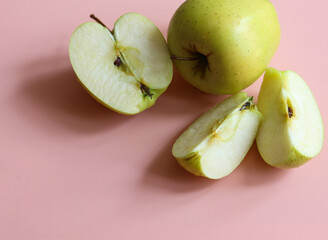 whole and sliced apples on a pink background