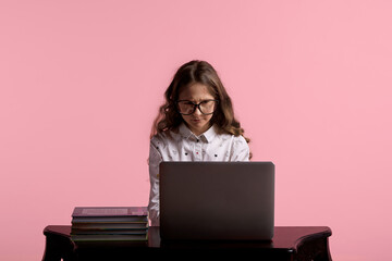 Naklejka premium girl with glasses for vision sits at a wooden table with a laptop