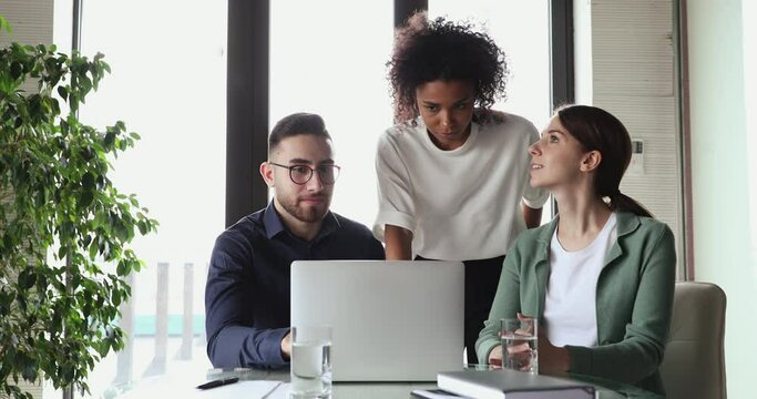Multiethnic business team people brainstorm using laptop computer at workplace. Afro american, caucasian and arab coworkers group group discuss corporate project software in teamwork at office desk.