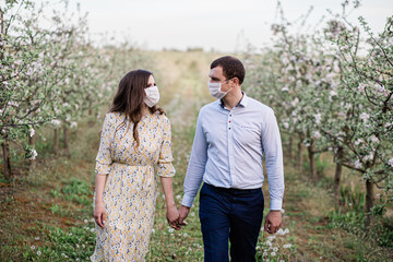 lovely masked couple walks in the garden in nature