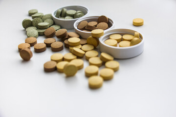 Supplements are scattered on the surface of the table close-up. White background. Vitamins and food additives help take care of health, have natural plant components and healthy nutrients.