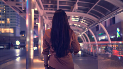Young asian woman walking in the night city streets