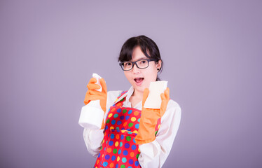 Asian Woman cleaning and polishing the kitchen worktop with a spray detergent, housekeeping and hygiene concept, accessories studio shot isolated on Gray background 