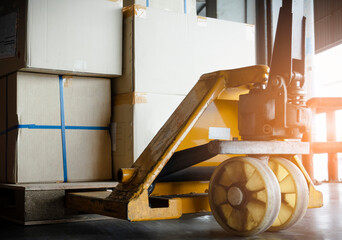 Closeup hand pallet truck with shipment boxes on pallet.
