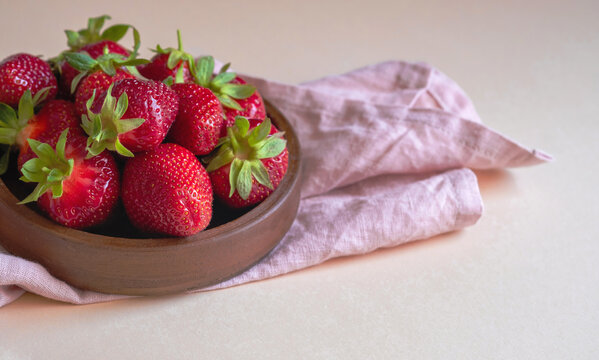 Fresh ripe delicious strawberries in a brown bowl on a light background. Copy space