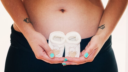 Small shoes for the fetus in the belly of the pregnant woman