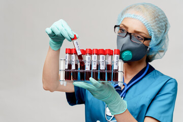 medical doctor nurse woman wearing protective mask and gloves - holding rack with virus blood tests