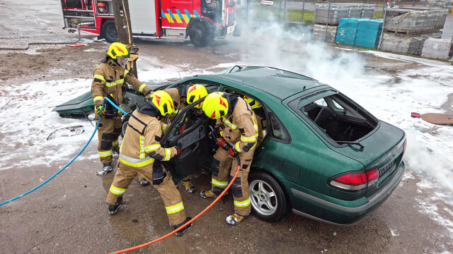 Team Off Firefighters Trying To Cut Open Car Door To Save Person Involved In The Accident. 