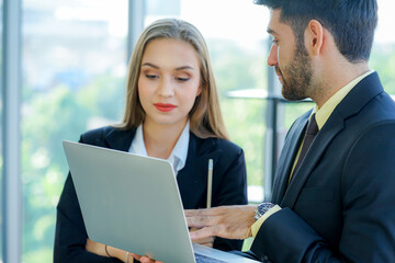 two young caucasian business womwan and colleage discuss the financial business plan from laptop comuter in the office