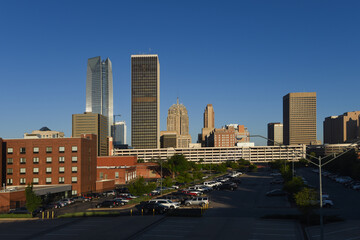 Looking across from Bricktown, towards downtown Oklahoma City with many tall buildings and bright early morning sunshine