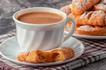 Coffee with cream and freshly baked puffs on a gray background