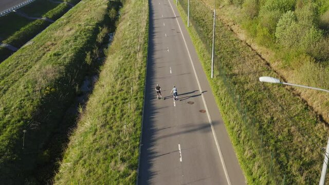 Aerial top view athletes on roller skis riding on road.