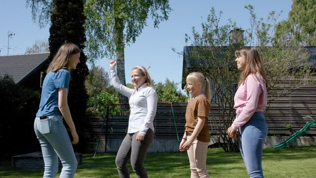 Family With Mother And Young Girls Practising Dance For TikTok In The Backyard