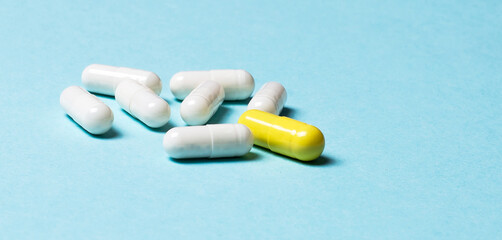 White and yellow capsules close-up on a blue background