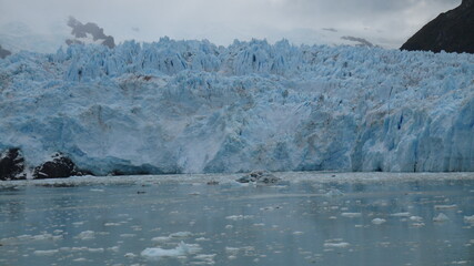 Panoramic views of a large glacier tongue on a blue lake with the high mountains of Canada in the background, and alpine scenery. We can see how the glacier has gone back in time