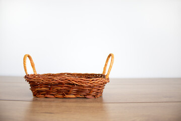 Obraz premium A small empty wicker basket on a beautiful wooden table, white background. Copy space.