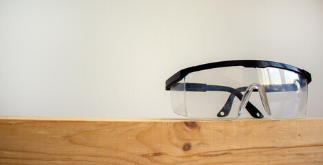 Safety glasses on a wooden bar. Beautiful white background. Copy space.