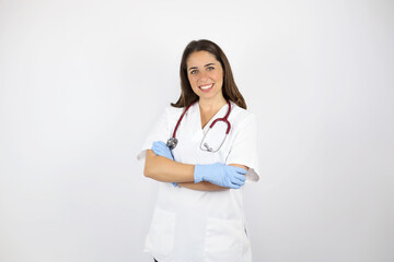 Young beautiful woman standing over white isolated background wearing her doctor uniform and smiling with arms crossed