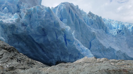 Panoramic views of a large glacier tongue on a blue lake with the high mountains of Canada in the...