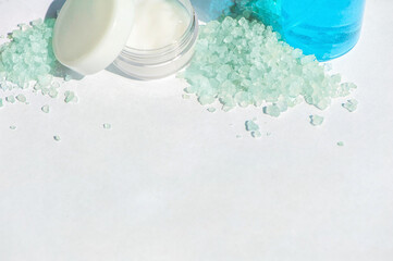 Blue gel in a bottle, white cup, blue bath salt, cream in a jar on a white background. Copy space