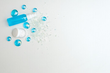 Blue gel spray, drops, glass, bath salt and moisturizer on a white background, top view. Copy space